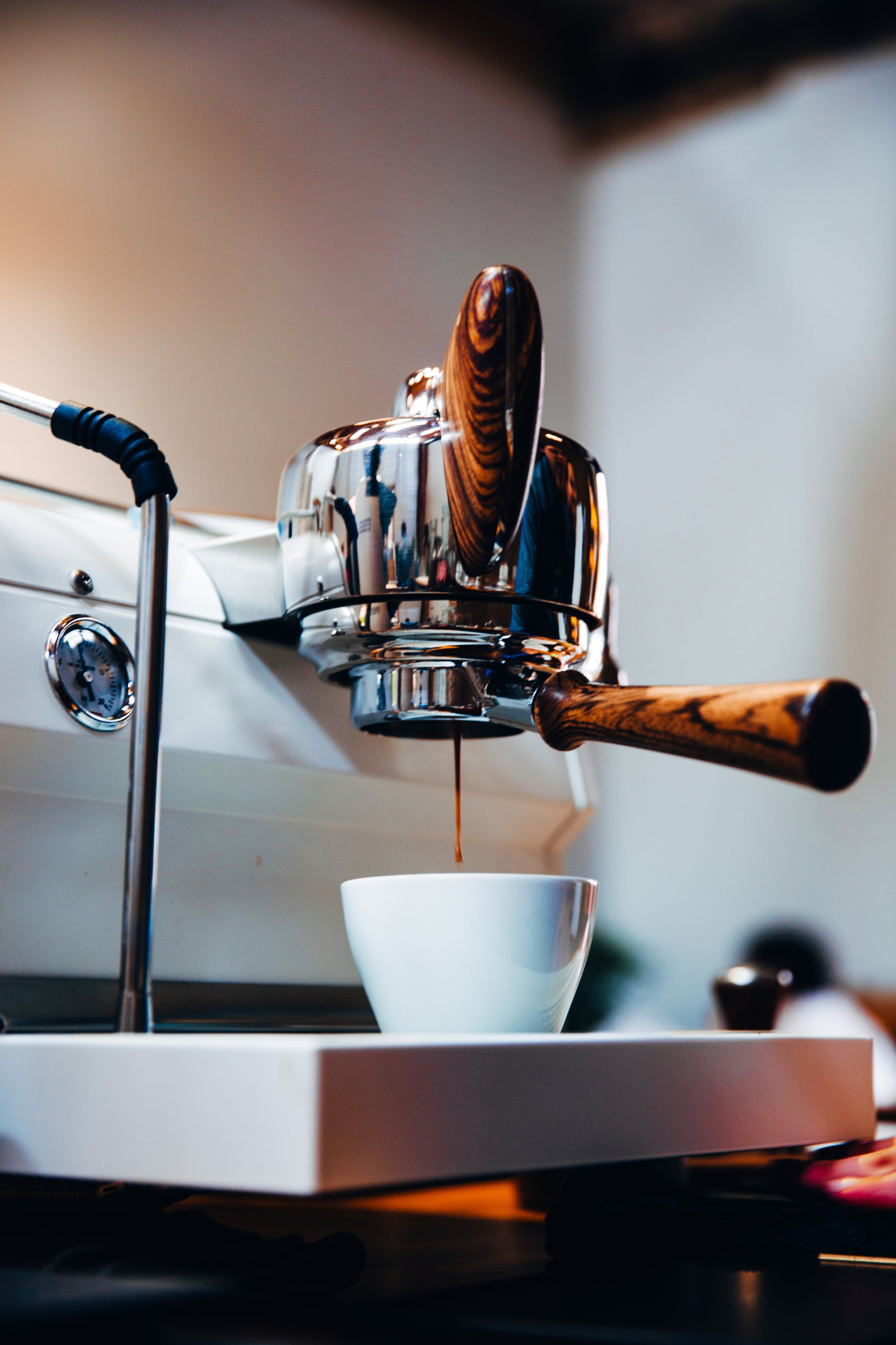 Traditional espresso machine with portafilter and steam wand used to prepare professional espresso and milk-based drinks.